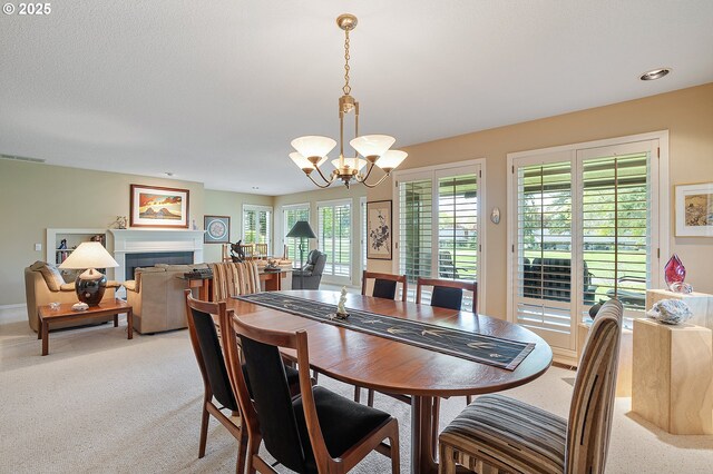 dining area featuring a chandelier, light carpet, and a tile fireplace