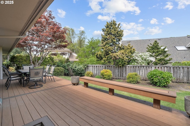 wooden deck with a fenced backyard and outdoor dining space