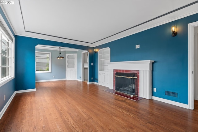 4621 NE 37th Ave, Portland, OR 97211 - unfurnished living room with built in features, baseboards, wood finished floors, crown molding, and a tiled fireplace