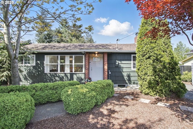 ranch-style house with roof with shingles and a chimney