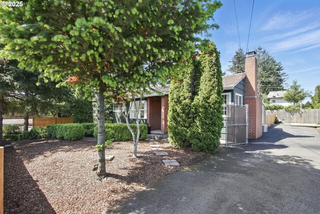 obstructed view of property featuring fence, brick siding, and a chimney