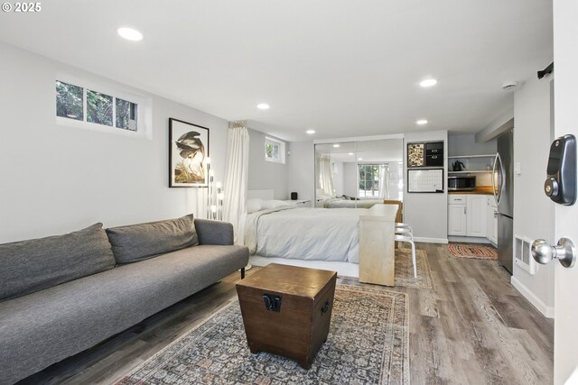 bedroom featuring freestanding refrigerator, wood finished floors, and recessed lighting