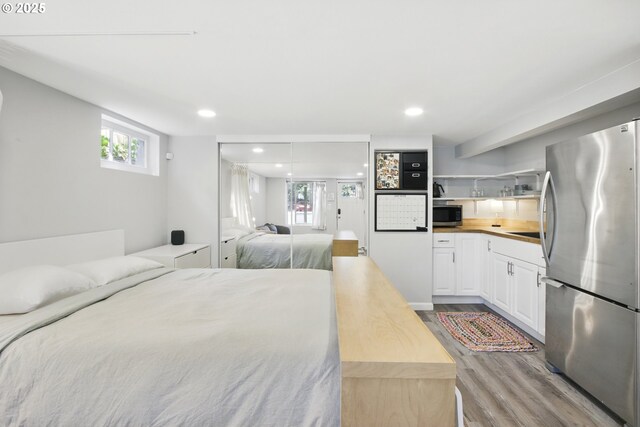 bedroom with freestanding refrigerator, wood finished floors, and recessed lighting