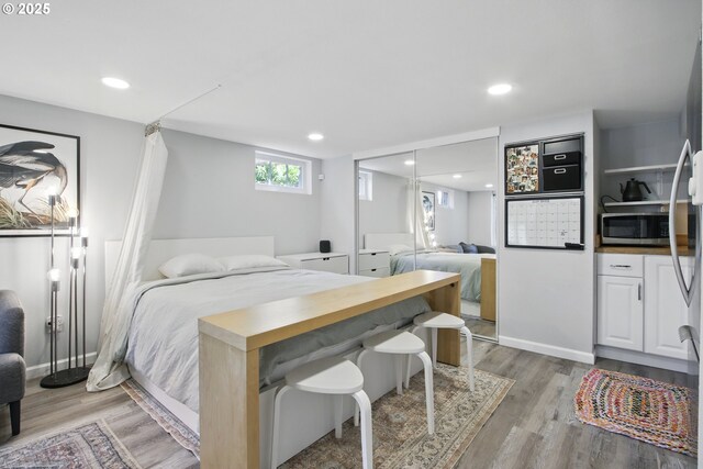 bedroom with light wood-type flooring, recessed lighting, and a closet