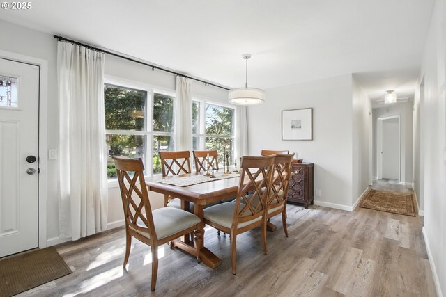 dining area with light wood-type flooring and baseboards