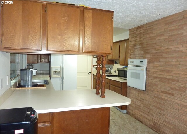 447 Cc St, Woodland, WA 98674 - kitchen featuring brown cabinetry, white appliances, a peninsula, light countertops, and a textured ceiling