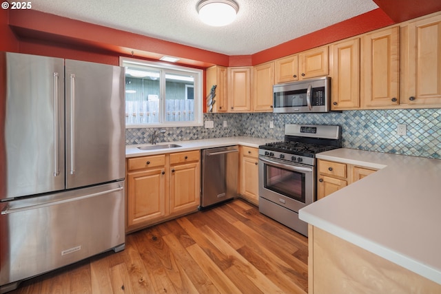 1378 SW Taylors Ferry Ct, Portland, OR 97219 - kitchen with appliances with stainless steel finishes, light wood-type flooring, light countertops, a textured ceiling, and backsplash