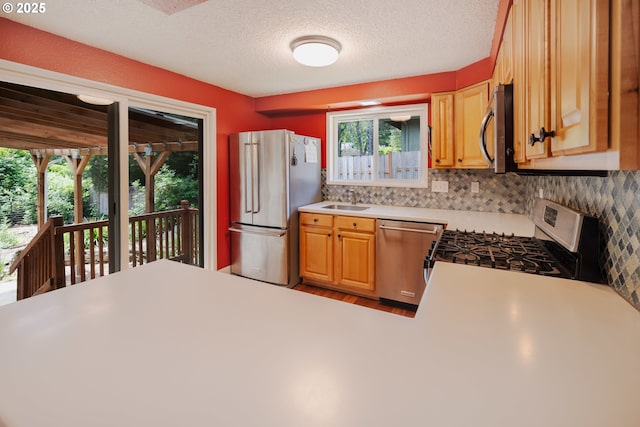 1378 SW Taylors Ferry Ct, Portland, OR 97219 - kitchen featuring stainless steel appliances, light countertops, tasteful backsplash, a textured ceiling, and wood finished floors