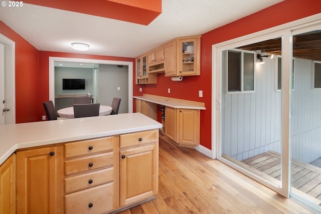 1378 SW Taylors Ferry Ct, Portland, OR 97219 - kitchen featuring light wood-style flooring, glass insert cabinets, light countertops, light brown cabinets, and a textured ceiling