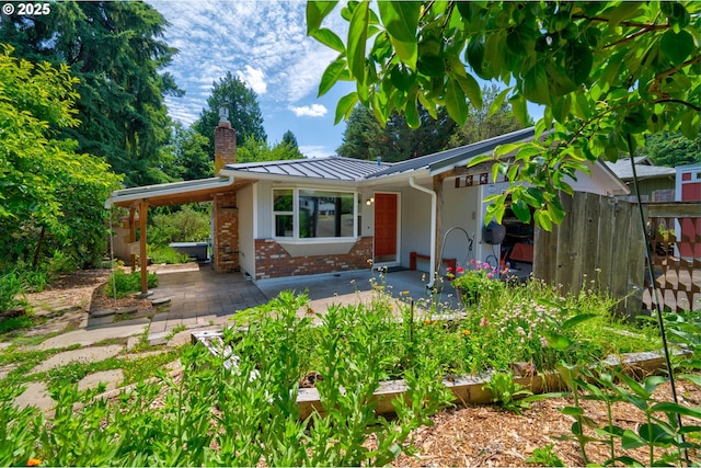 1378 SW Taylors Ferry Ct, Portland, OR 97219 - view of front of house with a chimney, a standing seam roof, a patio area, brick siding, and a metal roof