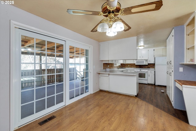 kitchen featuring a peninsula, white appliances, dark wood-type flooring, visible vents, and open shelves