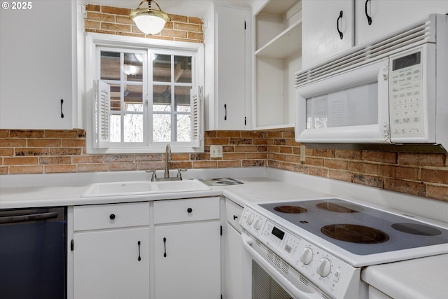 kitchen with white appliances, white cabinetry, and a sink