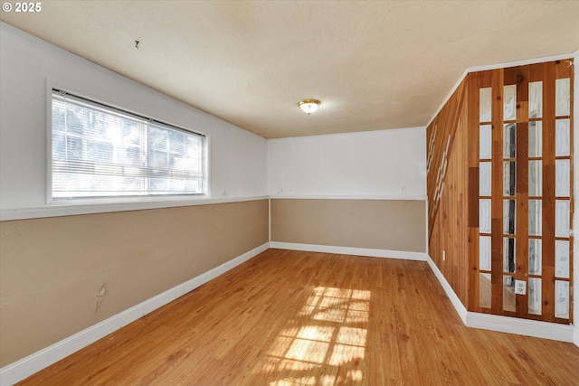 spare room featuring baseboards and wood finished floors