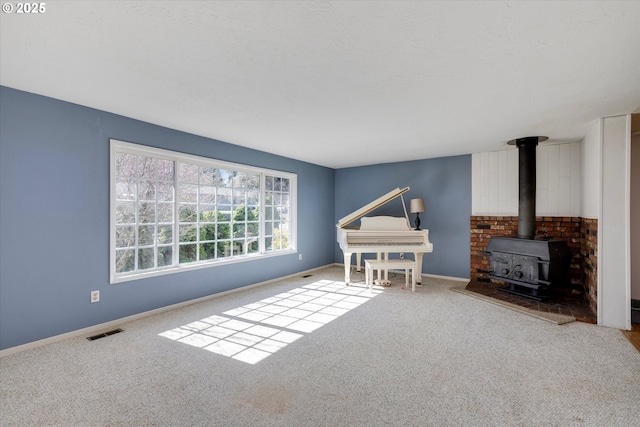 living area with a wood stove, visible vents, baseboards, and carpet flooring