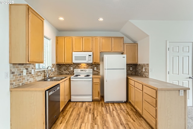 kitchen with a peninsula, light brown cabinets, white appliances, light wood-type flooring, and a sink