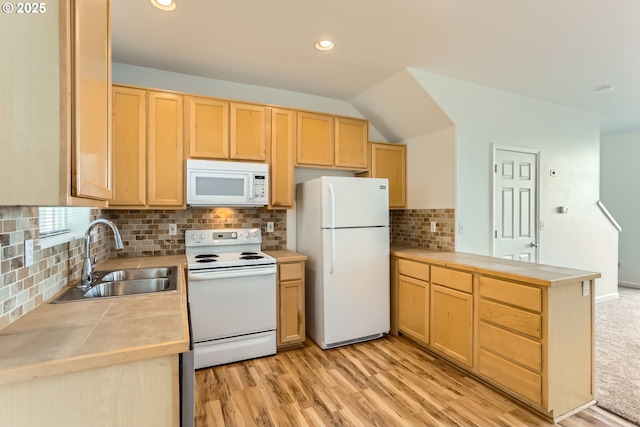 kitchen with a sink, a peninsula, light brown cabinets, white appliances, and light wood-style flooring