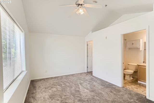unfurnished bedroom with carpet flooring, ensuite bath, vaulted ceiling, and multiple windows
