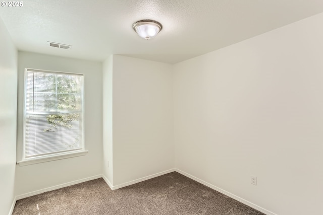 unfurnished room featuring a textured ceiling, baseboards, visible vents, and dark carpet