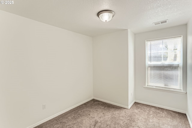 spare room featuring visible vents, a textured ceiling, baseboards, and light colored carpet