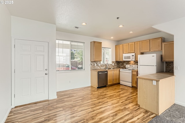 kitchen featuring a sink, light wood-style floors, white appliances, backsplash, and visible vents