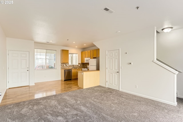 unfurnished living room featuring light colored carpet, a sink, recessed lighting, baseboards, and visible vents
