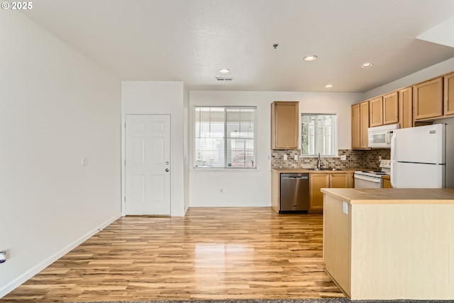 kitchen featuring decorative backsplash, a sink, light wood finished floors, recessed lighting, and white appliances