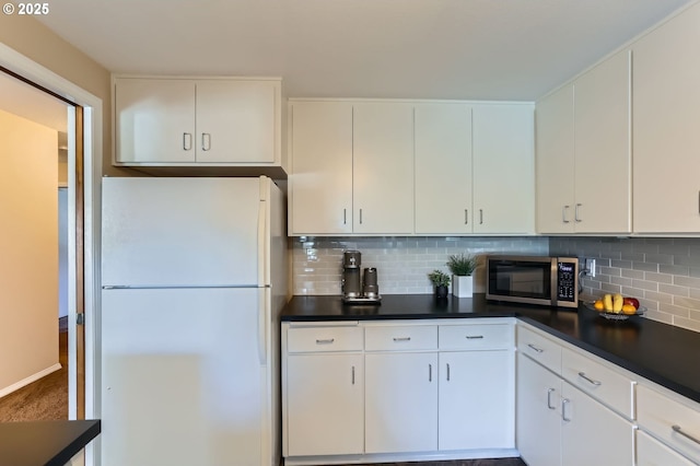 kitchen with freestanding refrigerator, stainless steel microwave, decorative backsplash, and dark countertops