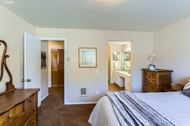 bedroom featuring heating unit, carpet, baseboards, and ensuite bath