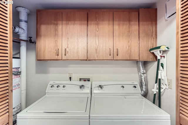 washroom featuring cabinet space, washing machine and clothes dryer, and a wall mounted air conditioner