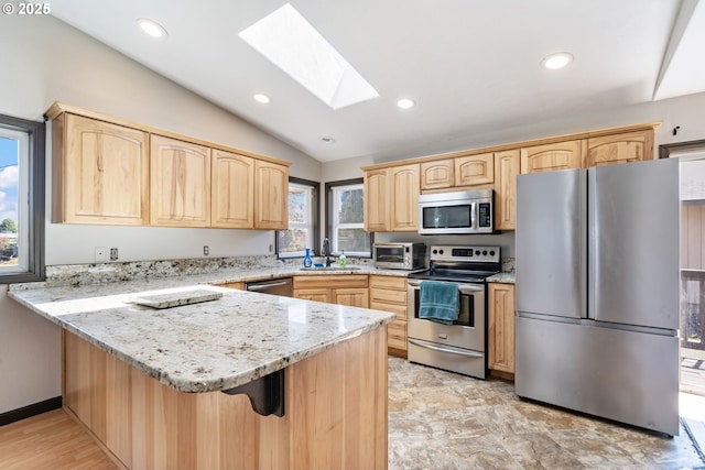 169 W 2nd St, Lafayette, OR 97127 - kitchen featuring appliances with stainless steel finishes, light brown cabinets, a peninsula, vaulted ceiling, and a skylight
