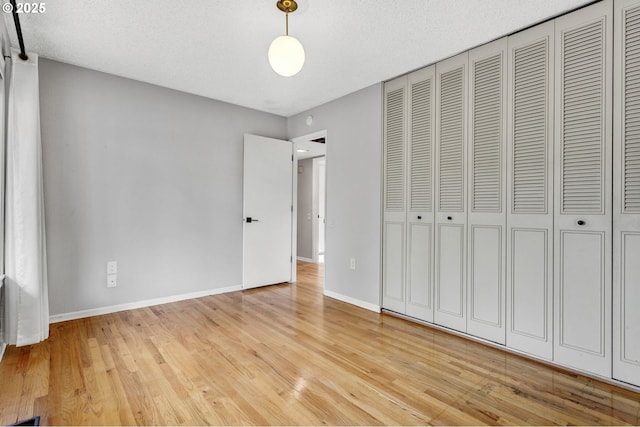 unfurnished bedroom with a closet, a textured ceiling, and light wood-type flooring