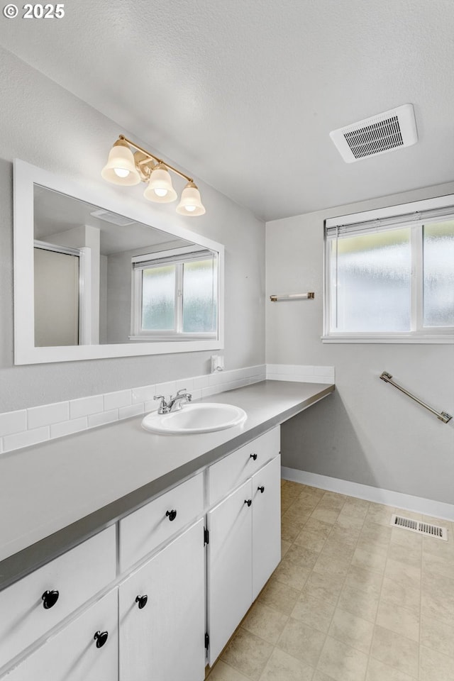 bathroom with vanity, an enclosed shower, and a textured ceiling