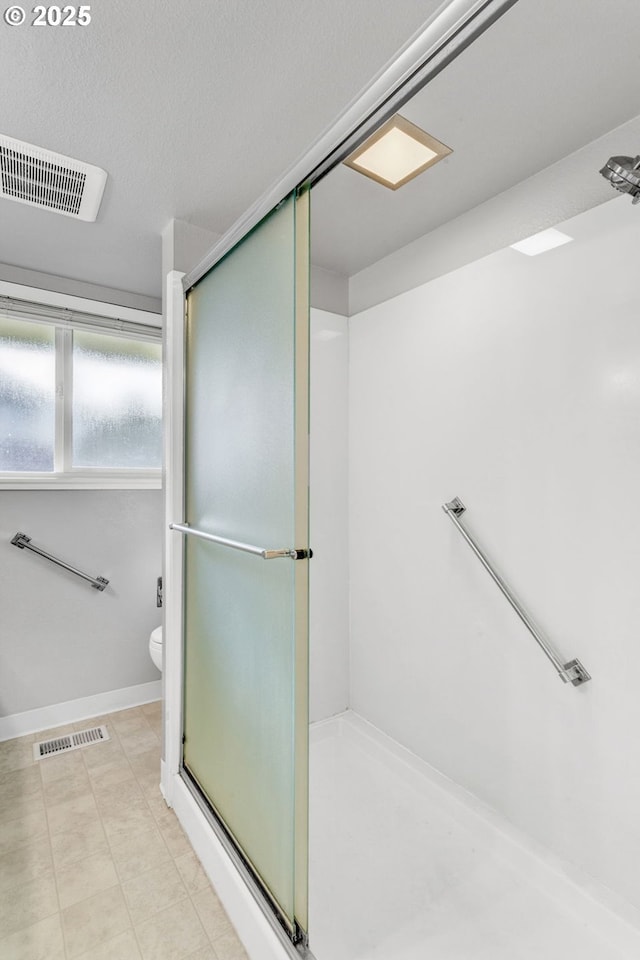 bathroom featuring a textured ceiling, toilet, and walk in shower