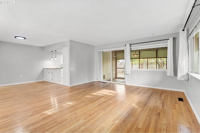 unfurnished living room featuring light hardwood / wood-style flooring and a textured ceiling