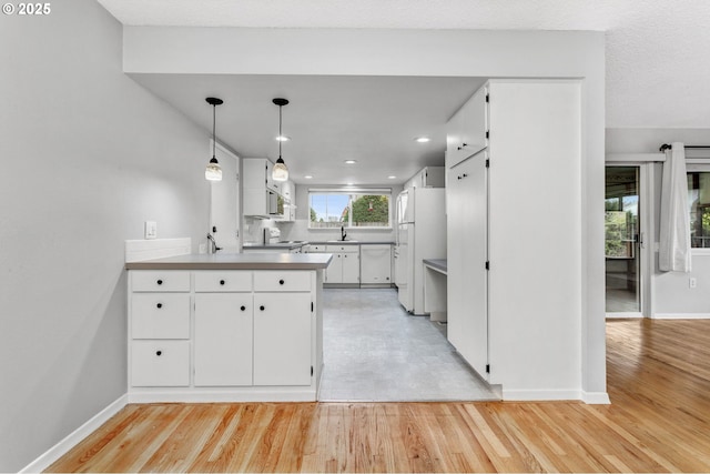 kitchen featuring decorative light fixtures, white cabinetry, sink, a barn door, and white appliances