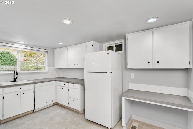 kitchen featuring white refrigerator, backsplash, sink, and white cabinets