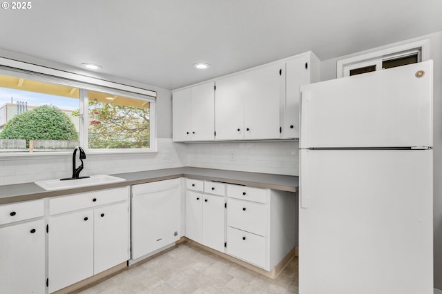 kitchen with white cabinetry, sink, backsplash, and white appliances