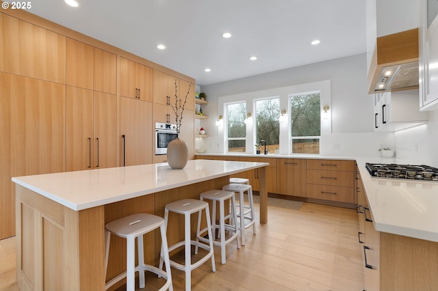 kitchen with a kitchen bar, light wood-style flooring, open shelves, recessed lighting, and appliances with stainless steel finishes