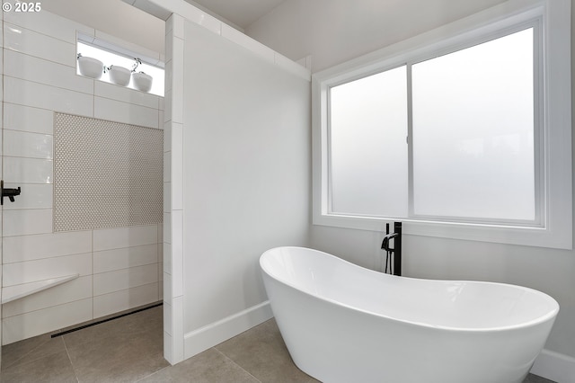 bathroom with tile patterned flooring, a freestanding tub, and baseboards