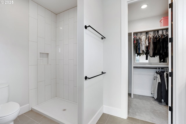 bathroom with tile patterned floors, a shower stall, toilet, and baseboards