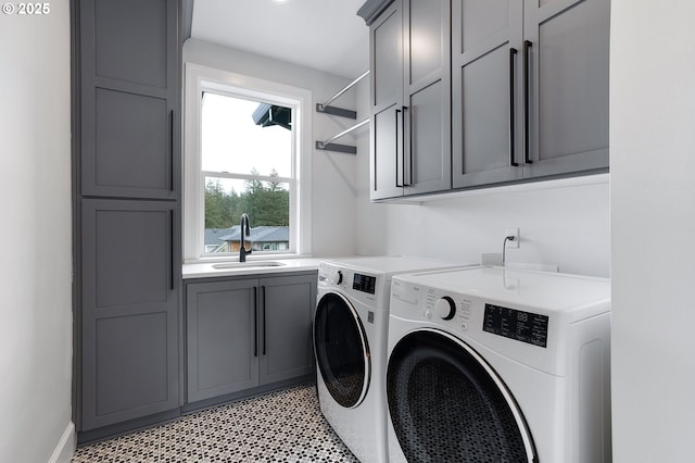 laundry area featuring washer and dryer, cabinet space, light floors, and a sink