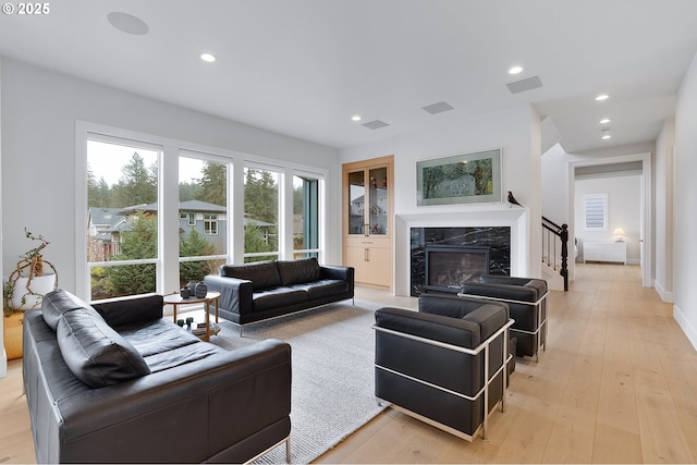 living room with light wood finished floors, visible vents, recessed lighting, and a premium fireplace