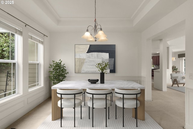 dining room featuring a chandelier, light colored carpet, wainscoting, breakfast area, and a tray ceiling