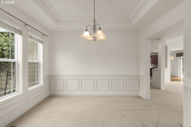 unfurnished room featuring wainscoting, a tray ceiling, light colored carpet, and a chandelier