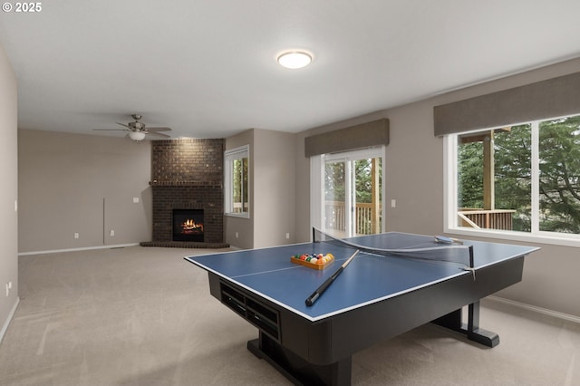 recreation room with baseboards, ceiling fan, light carpet, and a fireplace