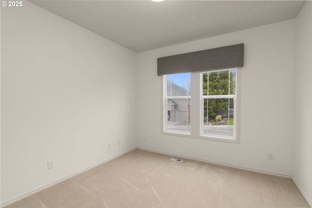 spare room with visible vents, baseboards, and light carpet