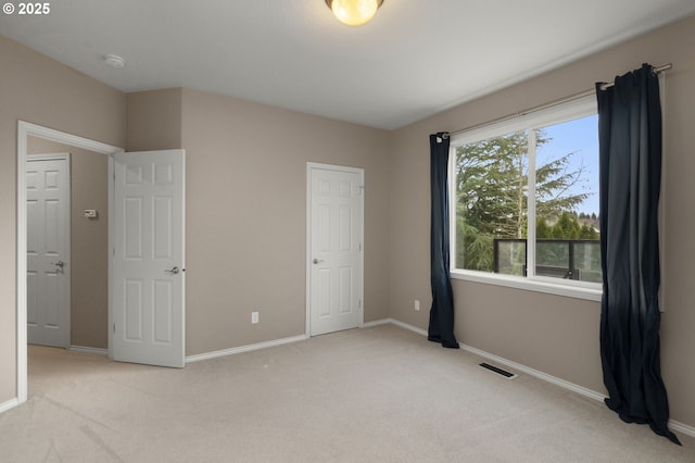 unfurnished bedroom featuring visible vents, baseboards, and light colored carpet