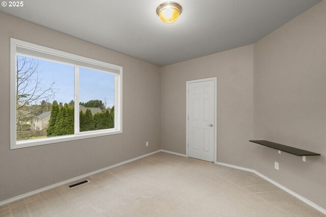 empty room featuring baseboards, light colored carpet, and visible vents