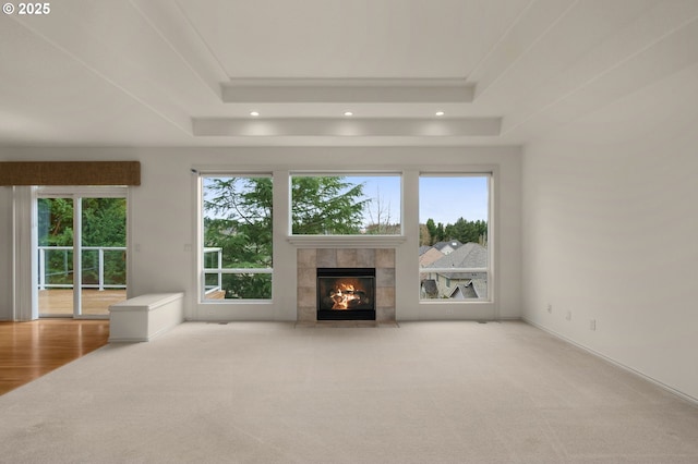 unfurnished living room with a raised ceiling, a fireplace, carpet flooring, and recessed lighting