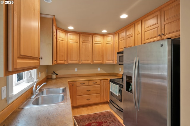 kitchen with stainless steel appliances, a sink, recessed lighting, light countertops, and light brown cabinetry